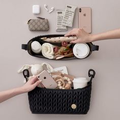 two women are holding their cell phones in an open purse with other items inside it