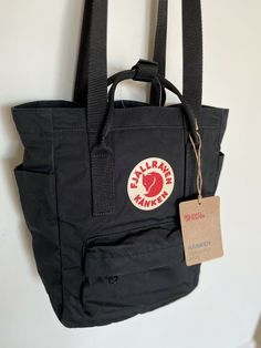 Fjallraven Unisex Black Kanken Tote Backpack mini Height: 30 cm Width: 25 cm Depth: 13 cm Volume: 8 l Laptop case: Yes Weight: 350 g Nursing Backpack, Kanken Aesthetic, Fjallraven Mini, Kanken Bag, School Aesthetics, Messanger Bag, School Bag Essentials, Bag Essentials, Bags Aesthetic