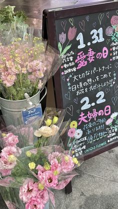 flowers are arranged in buckets next to a chalkboard with the date on it