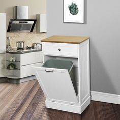 a kitchen with white cabinets and wood flooring is shown in this image, there is a trash can next to the sink