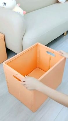 two boxes sitting next to each other on the floor in front of a white couch