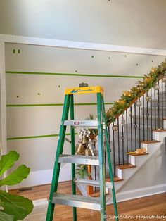 a ladder with christmas garland on it next to a staircase