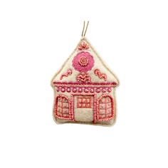 a pink and white house ornament hanging from a string