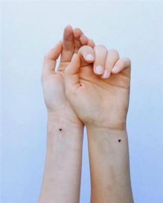 two hands holding each other with small black dots on their wrist and one hand in the air