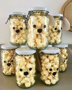 there are many jars with popcorn in them and a teddy bear face on the top