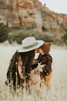 two women are sitting in the tall grass and one is holding her head to her chest