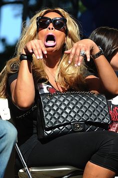 a woman sitting in a chair with her mouth open and holding a purse over her shoulder