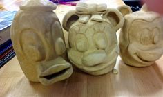 three clay sculptures sitting on top of a wooden table