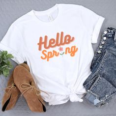 Hello Spring Tshirt!! Cute tee to get you in the spring mood. good for gifts. cute pastel tshirt with flowers. cute tshirt with pastel font. tshirt with cute font. spring tshirts with flowers. tshirt for everyone.  This classic unisex jersey short sleeve tee fits like a well-loved favorite. Soft cotton and quality print make users fall in love with it over and over again. These t-shirts have-ribbed knit collars to bolster shaping. The shoulders have taping for better fit over time. Dual side seams hold the garment's shape for longer.  .: 100% Airlume combed and ringspun cotton (fiber content may vary for different colors) .: Light fabric (4.2 oz/yd² (142 g/m .: Retail fit .: Tear away label .: Runs true to size Spring Letter Print Short Sleeve T-shirt, White T-shirt With Funny Print For Spring, Cute Spring T-shirt With Funny Text, White Letter Print T-shirt For Spring, Spring Crew Neck T-shirt With Text Print, Casual Tops With Funny Text For Spring, Cute White T-shirt For Spring, Cute Spring Letter Print T-shirt, Spring T-shirt With Text Print