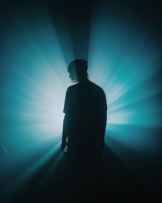 a man standing in the middle of a dark room with light coming from behind him