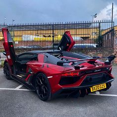 a red sports car parked in a parking lot with its doors open and the door opened