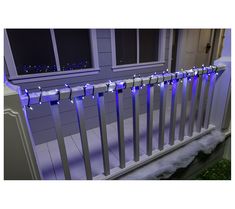 blue lights are on the side of a white railing in front of a building with windows