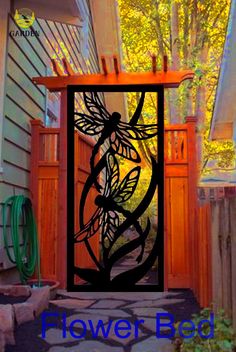 an iron gate with the words flower bed on it in front of a house and trees