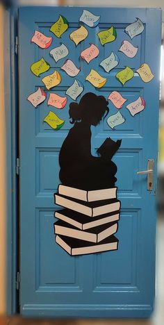 a door decorated with books and a silhouette of a woman reading on top of them