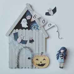 a wooden house with halloween decorations on the outside and a doll standing next to it