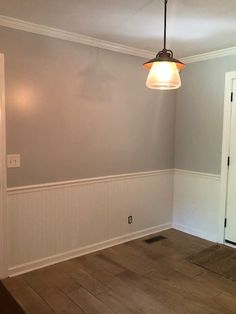 an empty room with hard wood floors and gray walls