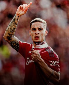 a man with tattoos on his arms and arm is pointing to the side while wearing a red shirt