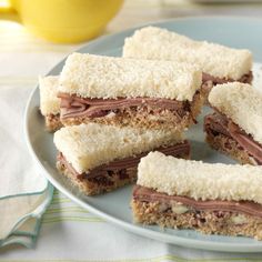 a plate topped with cut in half sandwiches on top of a cloth covered tablecloth