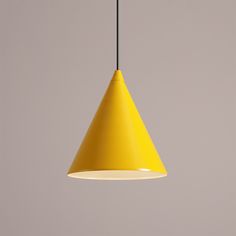 a yellow light hanging from a ceiling in front of a gray wall with a black cord