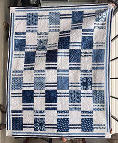 a blue and white quilt hanging from the side of a building