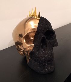 a gold skull with a crown on it's head sitting on a black table