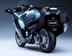 a black and silver motorcycle parked on top of a white floor next to a gray wall