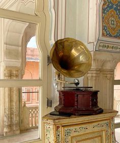 an old phonograph sitting on top of a table in front of a window