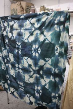 a blue and white tie - dyed cloth hanging on a clothes rack in a room