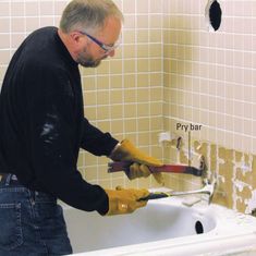 a man in black shirt and yellow gloves fixing a bathtub