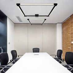 an empty conference room with black chairs and a white table