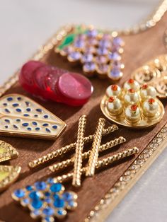 a wooden tray with various types of jewelry on it's side, including brooches and earrings