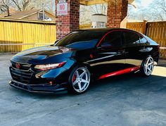 a black car parked in front of a gas station with red stripes on the side