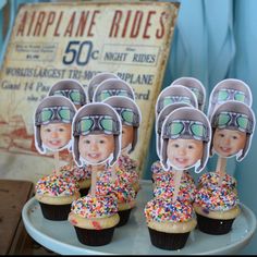 cupcakes with helmets and sprinkles are on a plate next to an old sign