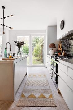 a white kitchen with an area rug on the floor