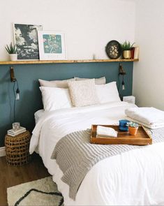 a bed with white linens and pillows in a bedroom next to a wooden shelf