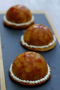 three baked desserts sitting on top of a black tray with white trim around the edges