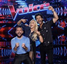 two men and a woman standing in front of a wall with the voice written on it