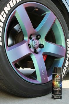 a purple and blue wheel next to a can of spray paint on the side of a car