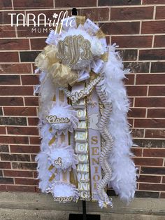 a white and gold mardi gras costume on a stand in front of a brick wall