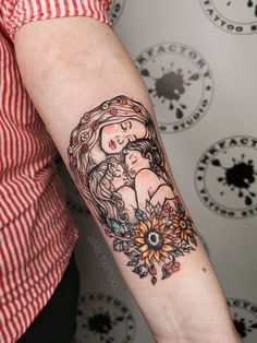 a woman with a tattoo on her arm holding a baby in her arms and sunflowers