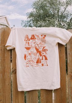 an orange and white t - shirt hanging on a wooden fence