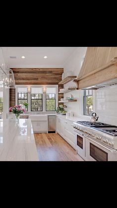 a large kitchen with white cabinets and wooden walls, along with an island in the middle