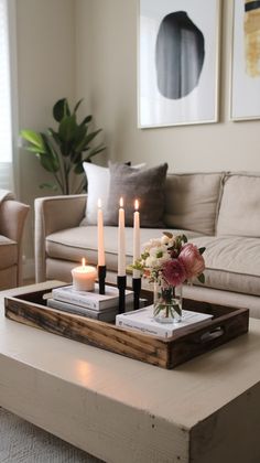 two candles are sitting on a tray in the middle of a living room with couches