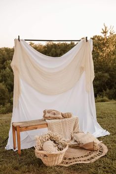 an old fashioned chair and blanket on the grass in front of a white sheet draped over it