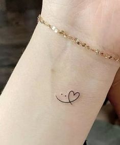 a woman's wrist with a small heart tattoo on the left side of her arm