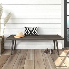 a wooden bench sitting on top of a hard wood floor next to a white wall