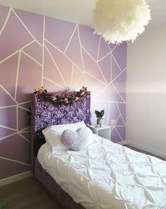 a white bed sitting under a purple and white wall