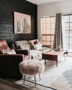 a living room filled with furniture and a painting on the wall next to a window