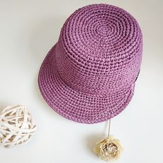 a purple crocheted hat next to a white flower