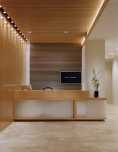 an empty reception area with a television and plant in the center, along with wooden paneling